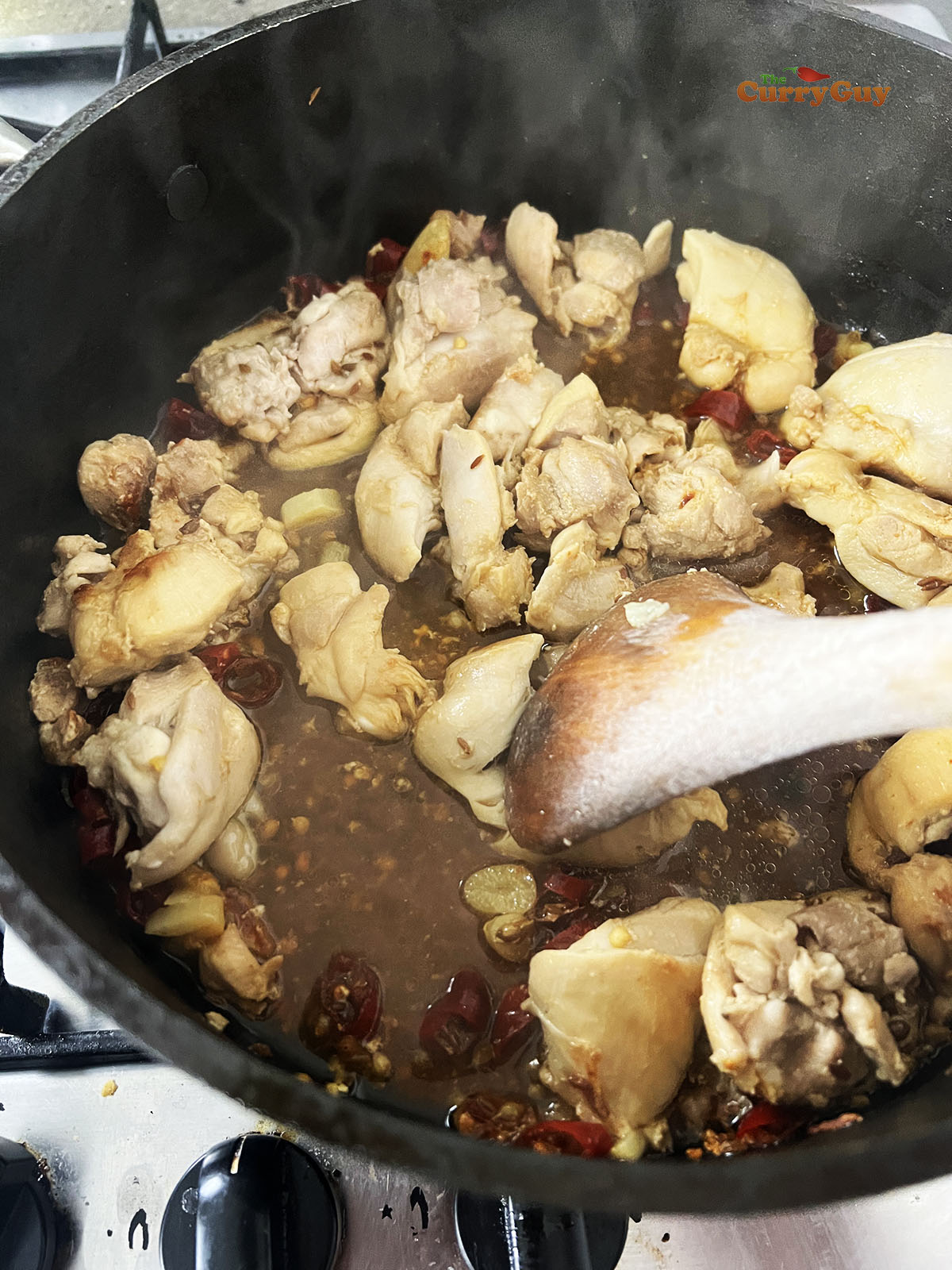 Adding water to the pan to simmer the chicken.
