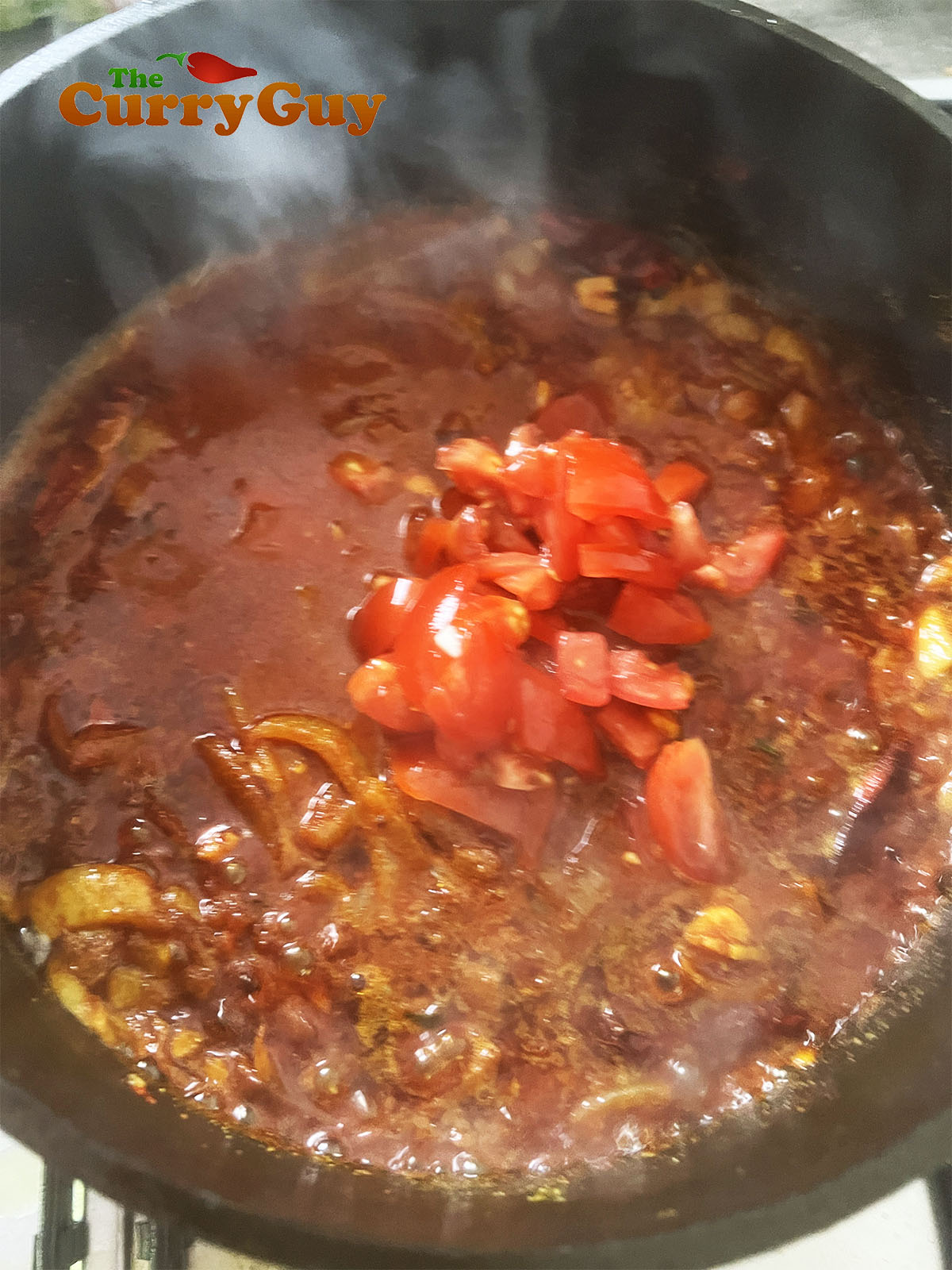 Adding water and tomatoes to the pan.