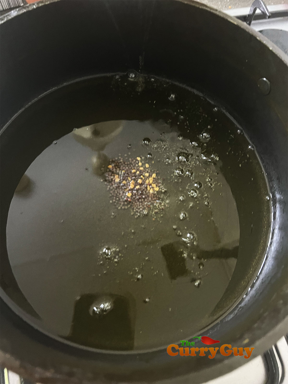 Infusing fenugreek and mustard seeds in the oil.