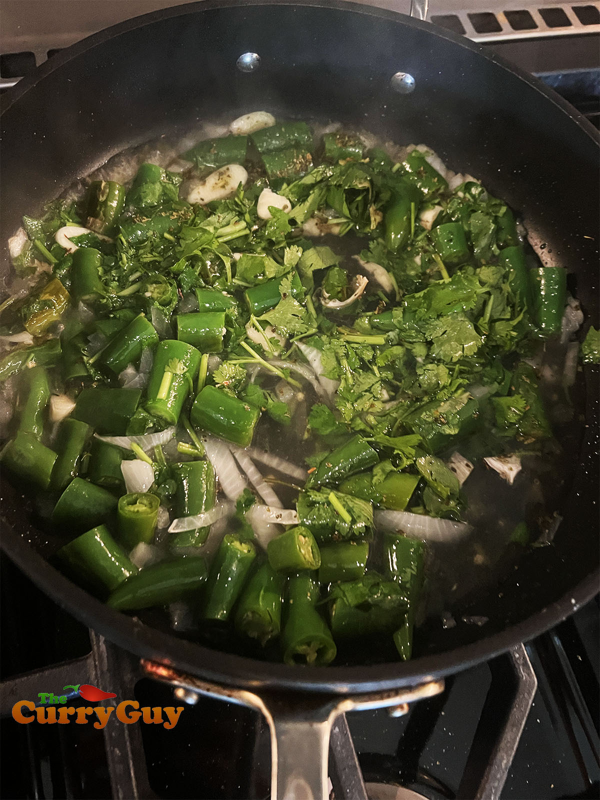 Simmering the onions and chilies in water and vinegar to soften.