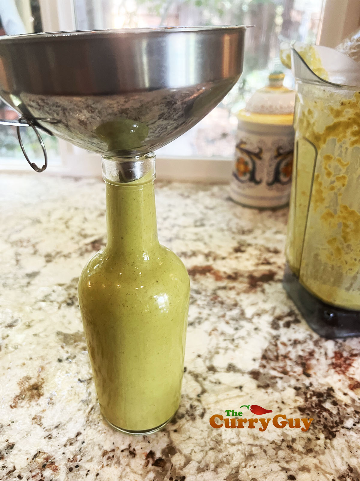 Pouring the hot sauce through a funnel into a bottle.