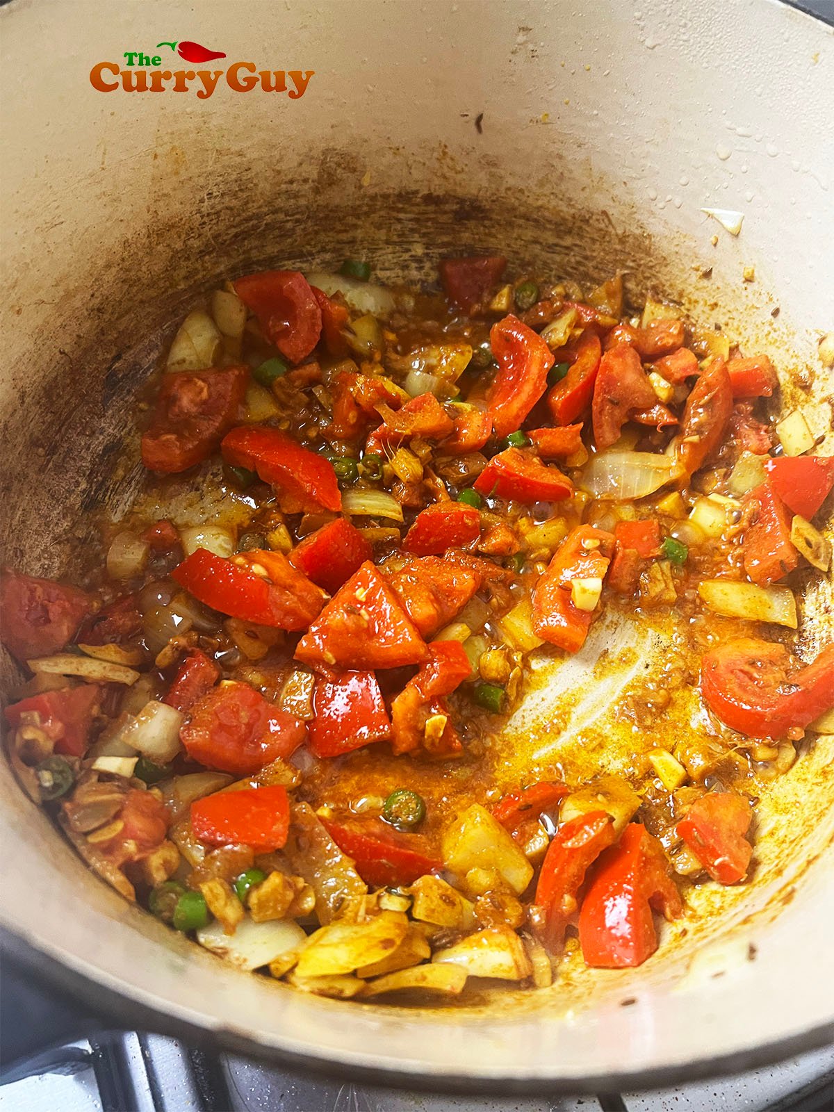 Adding chopped tomatoes and ground spices to the pan.