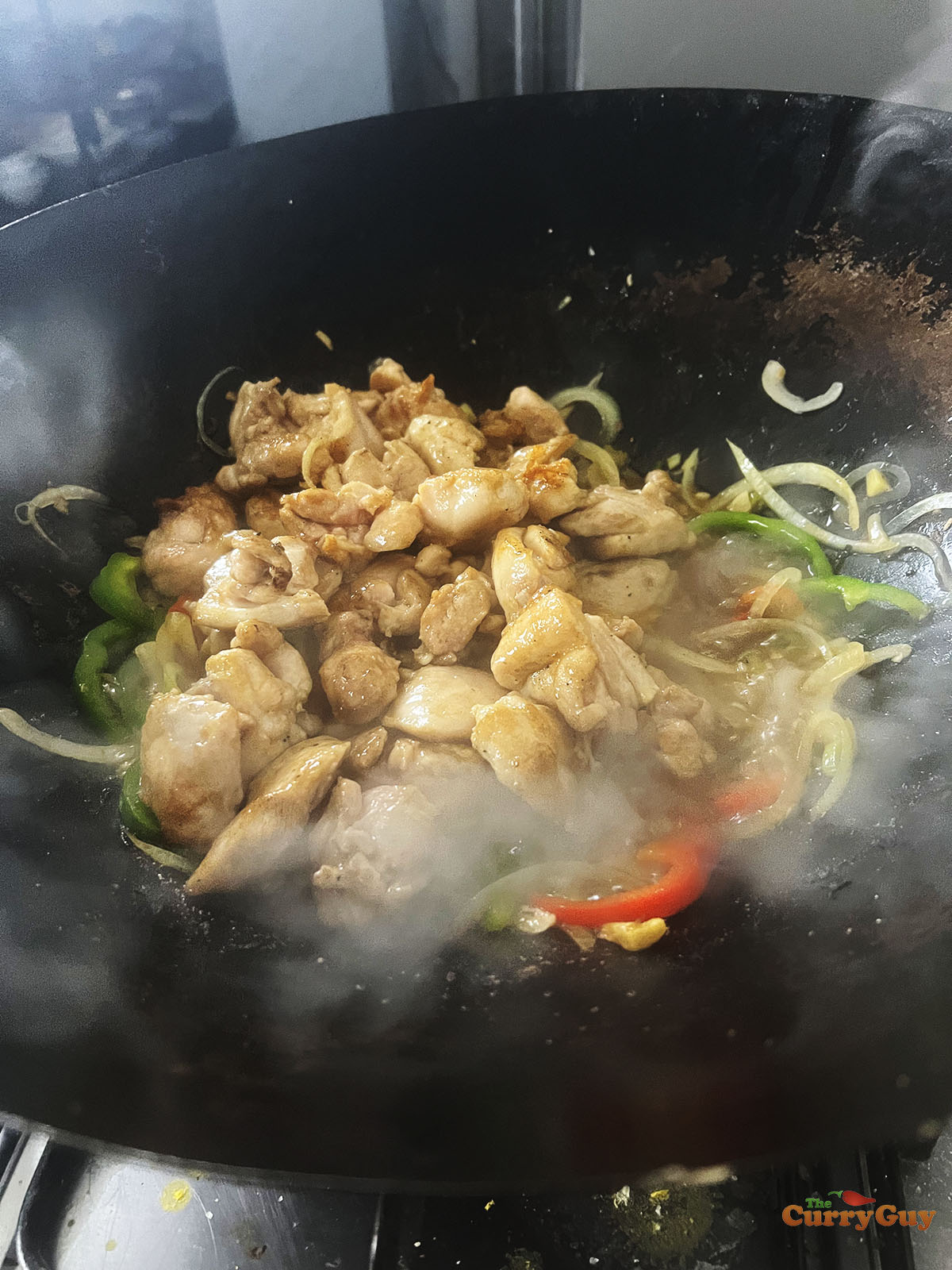 Returning the par-cooked chicken to the wok.