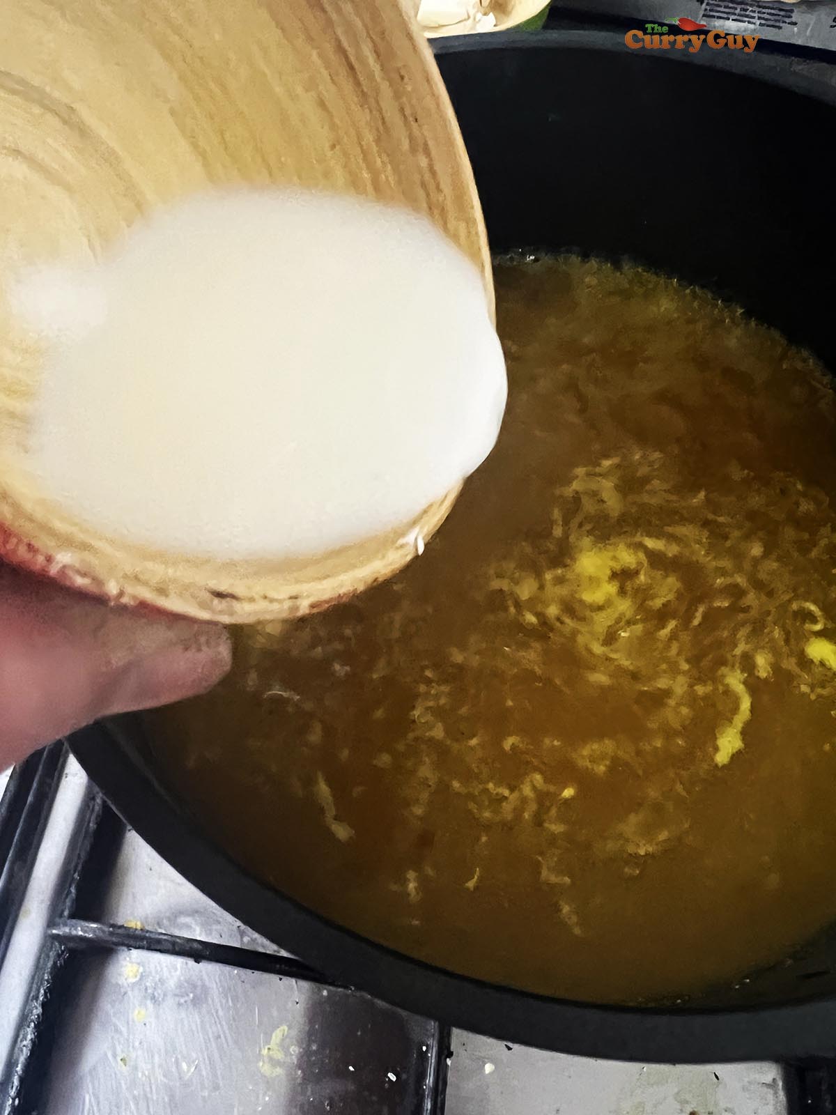 Adding a slurry to the soup to thicken.