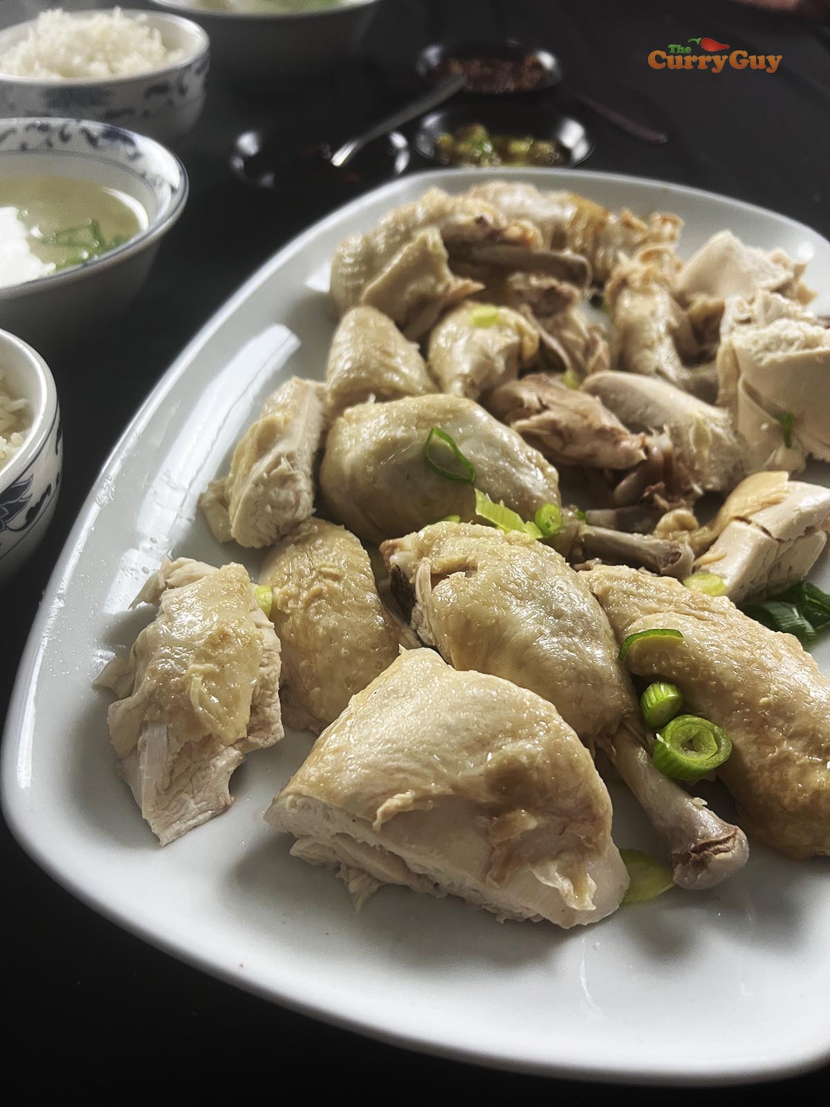 Serving the Hainan chicken at the table with dipping sauces, broth and rice.