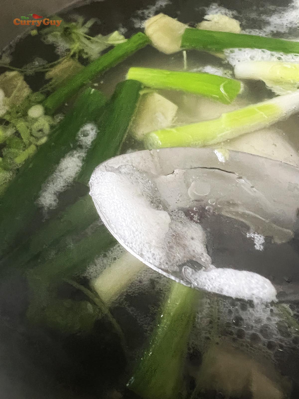 Skimming foam off the broth as it comes to a simmer.