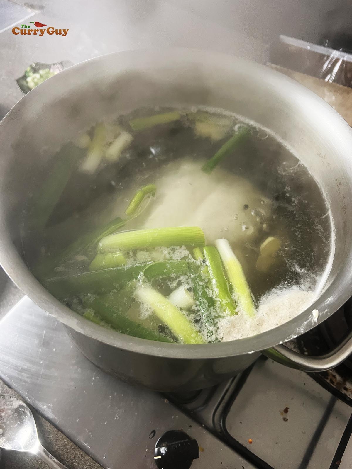 Simmering a chicken with aromatic ingredients.