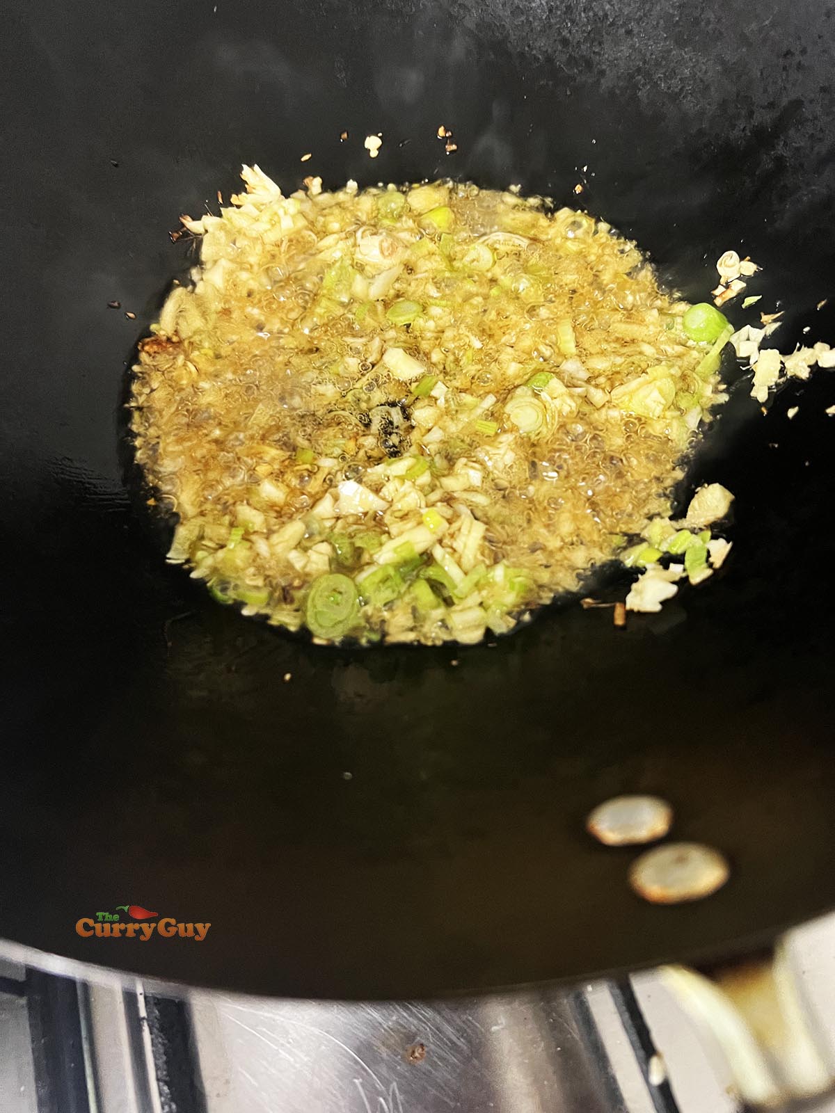 Frying garlic, ginger and spring onions (scallions).