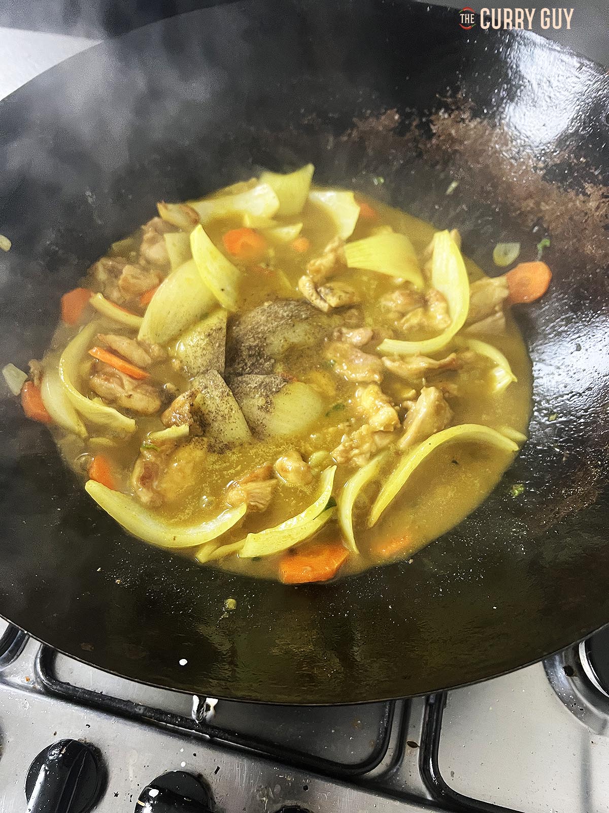 Adding the chicken stock and coconut milk to the wok.