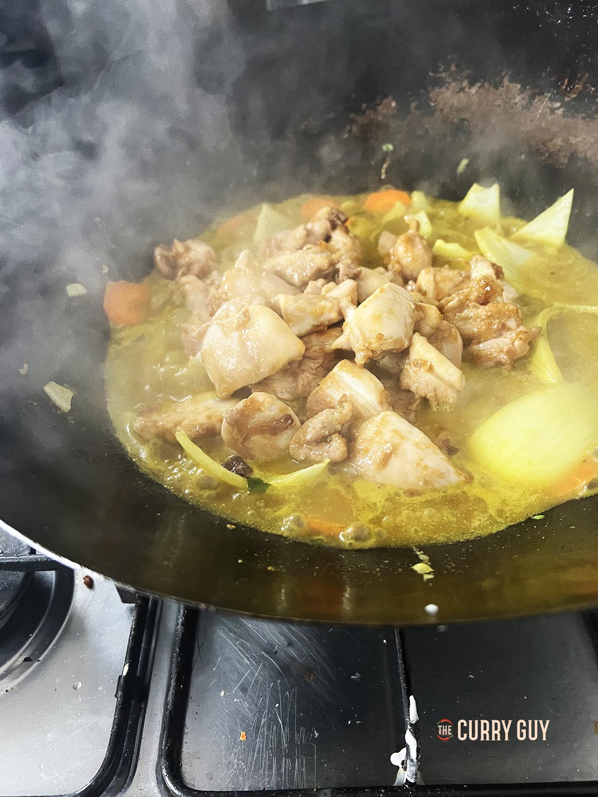 Adding the fried chicken to the simmering sauce.