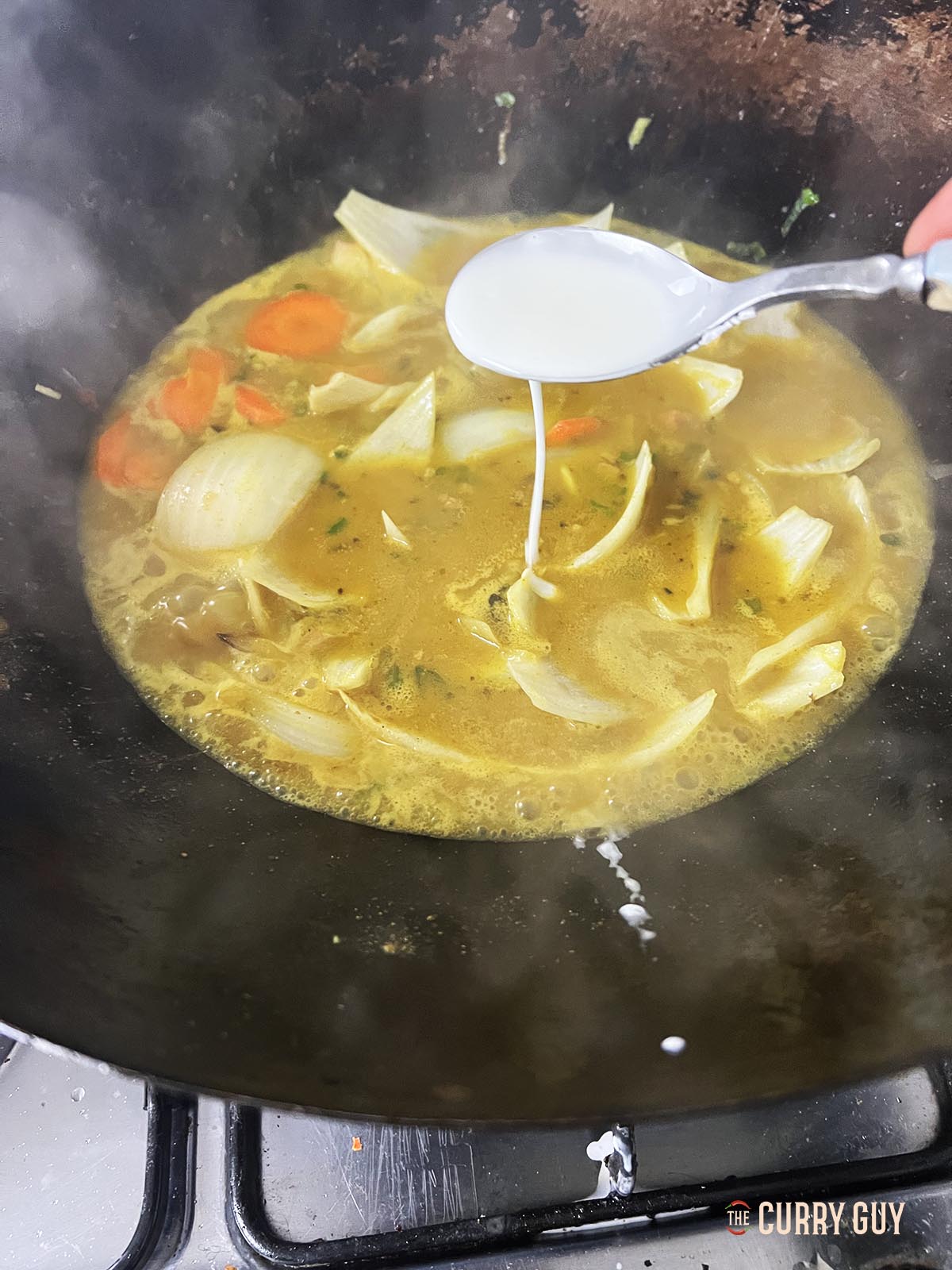 Adding the slurry to the sauce to thicken.