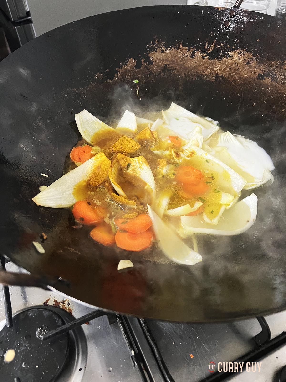 Adding curry powder to the ingredients in the wok.