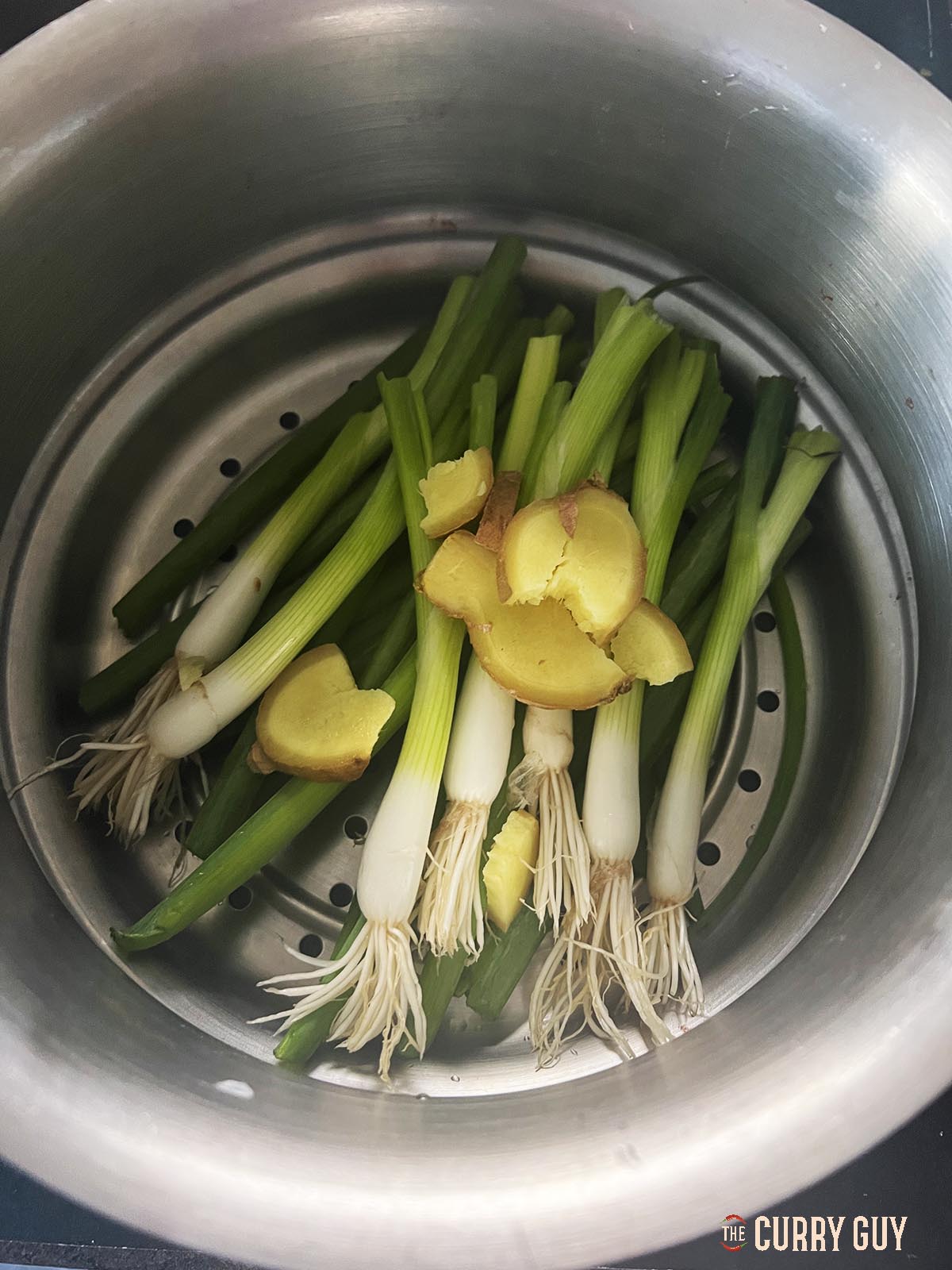 The ginger and spring onions (scallions) in a steamer.