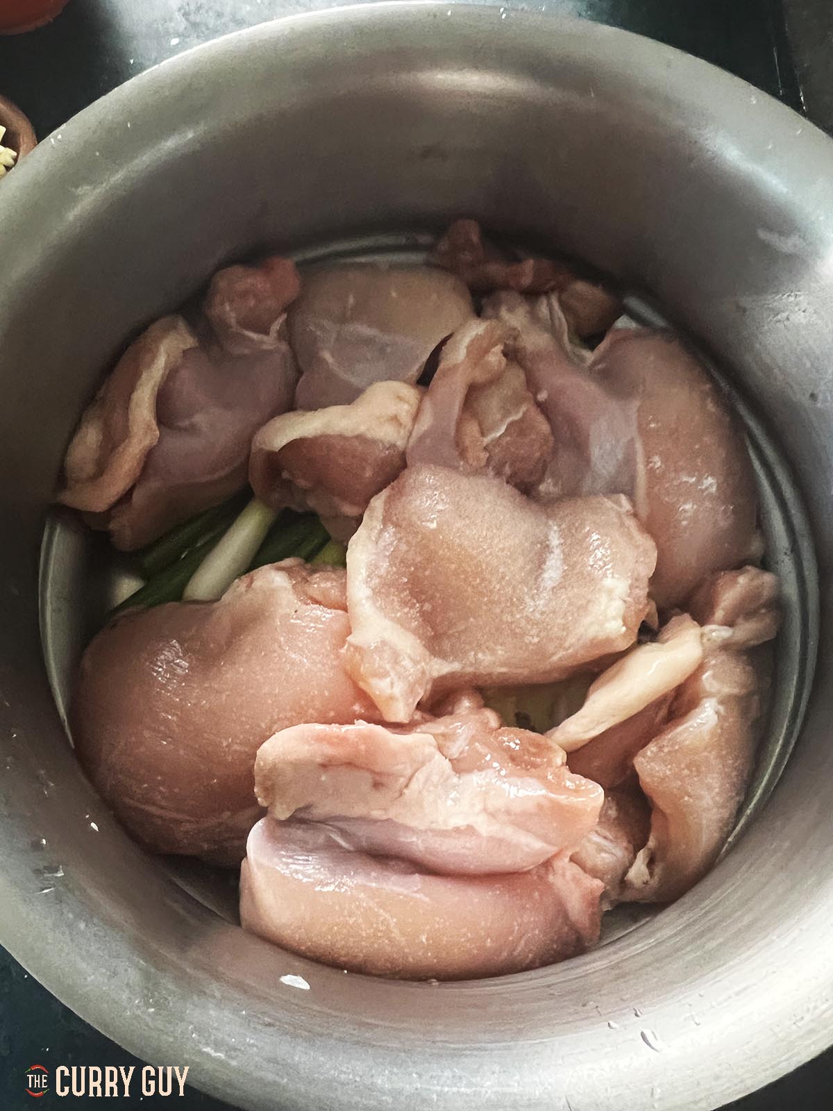 the chicken on top of the ginger and spring onions (scallions) in the steamer.