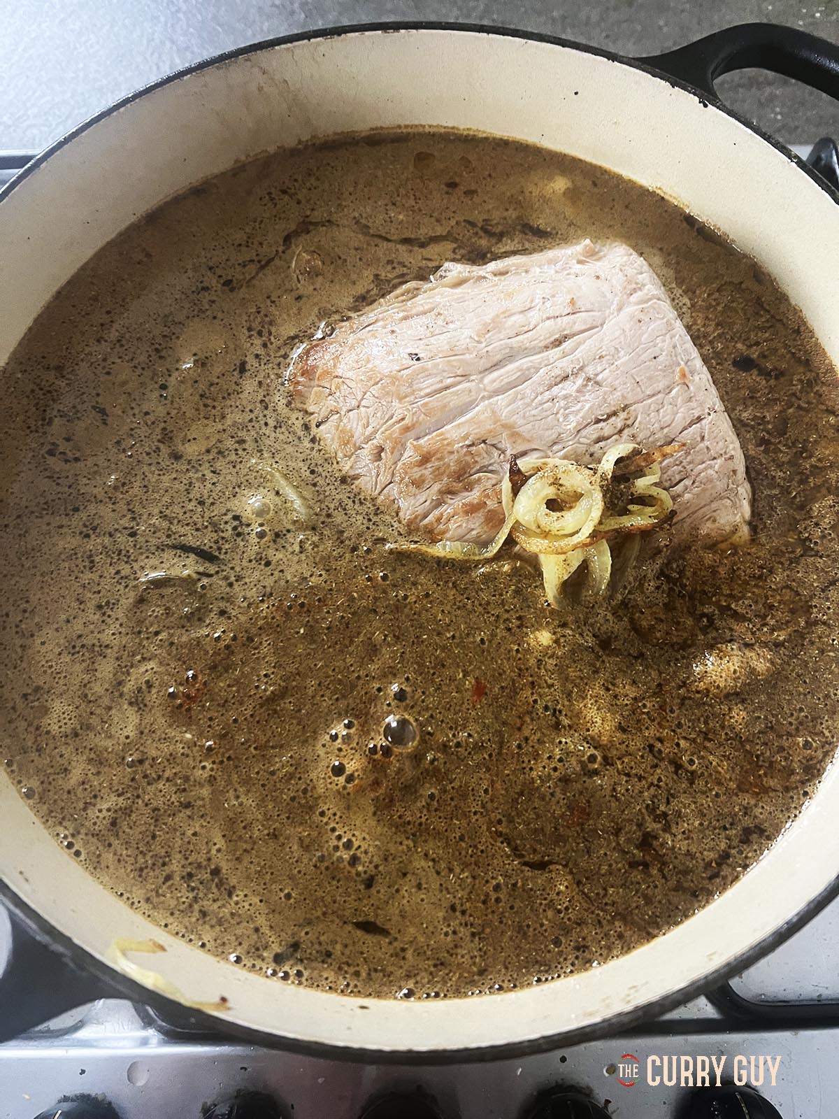 Adding water and then simmering the beef with the other ingredients. 