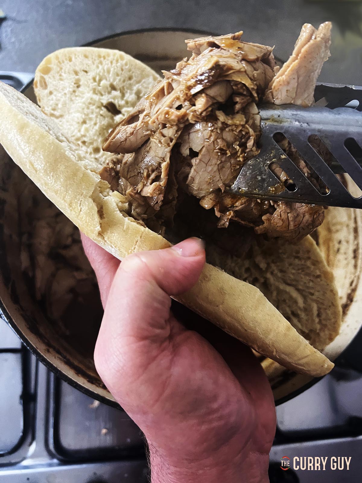 Placing some meat on a sourdough roll.