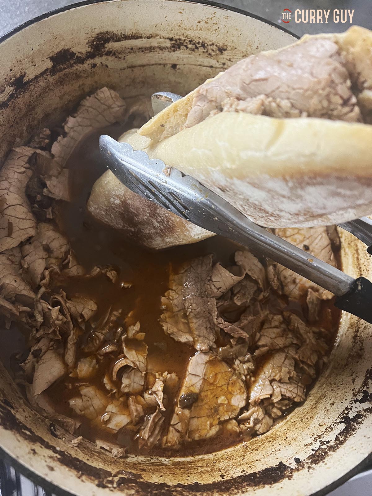 Dunking a beef nihari sandwich in the hot broth.