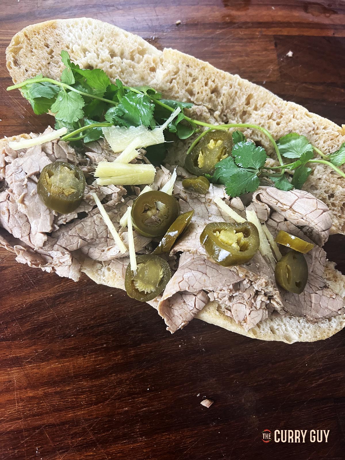 Topping the nihari sandwich with the garnishes.