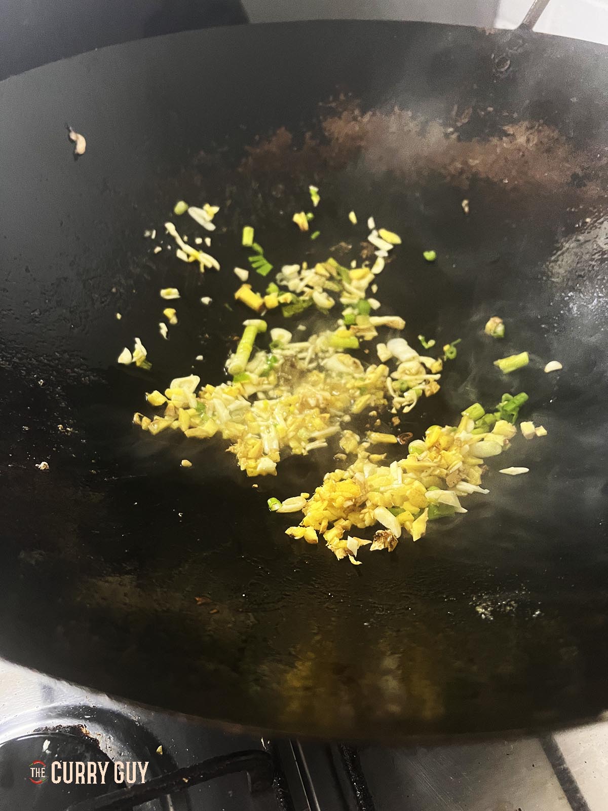 Frying the garlic, ginger and spring onions (scallions). 