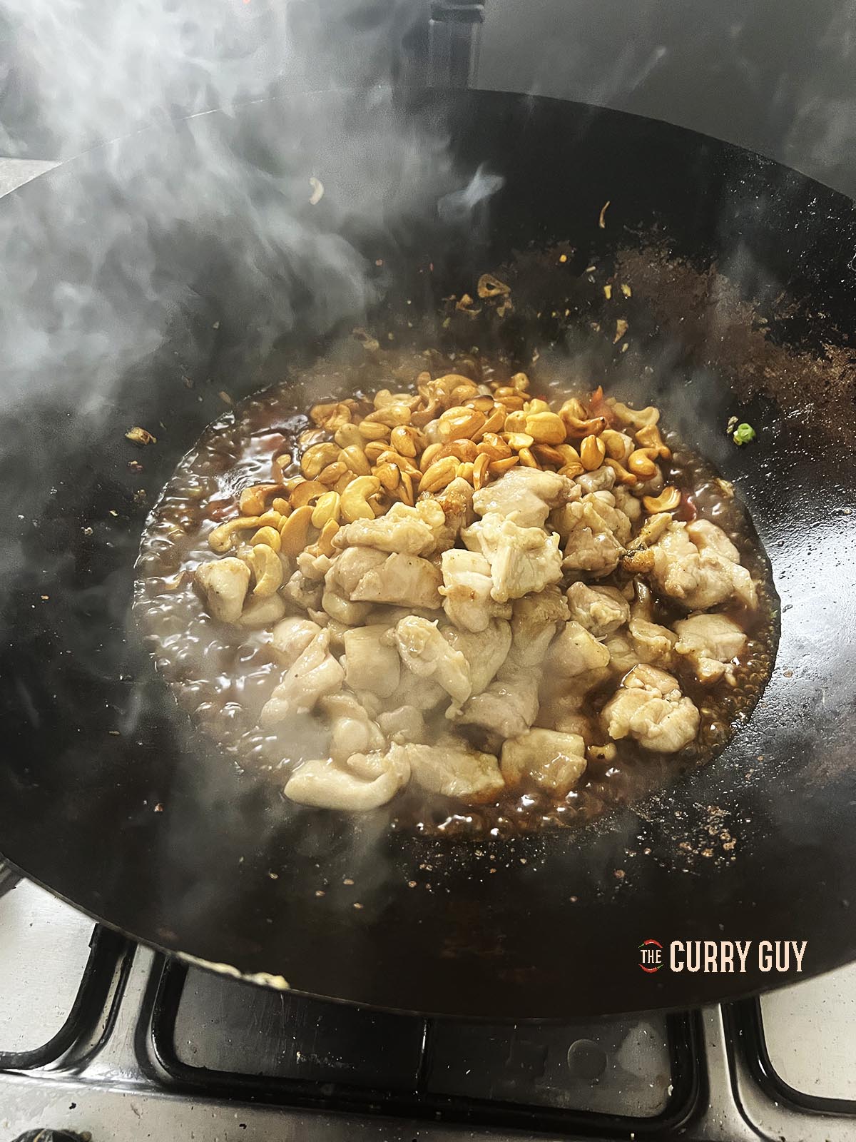 Returning the chicken pieces to the wok and also adding the roasted cashews. 