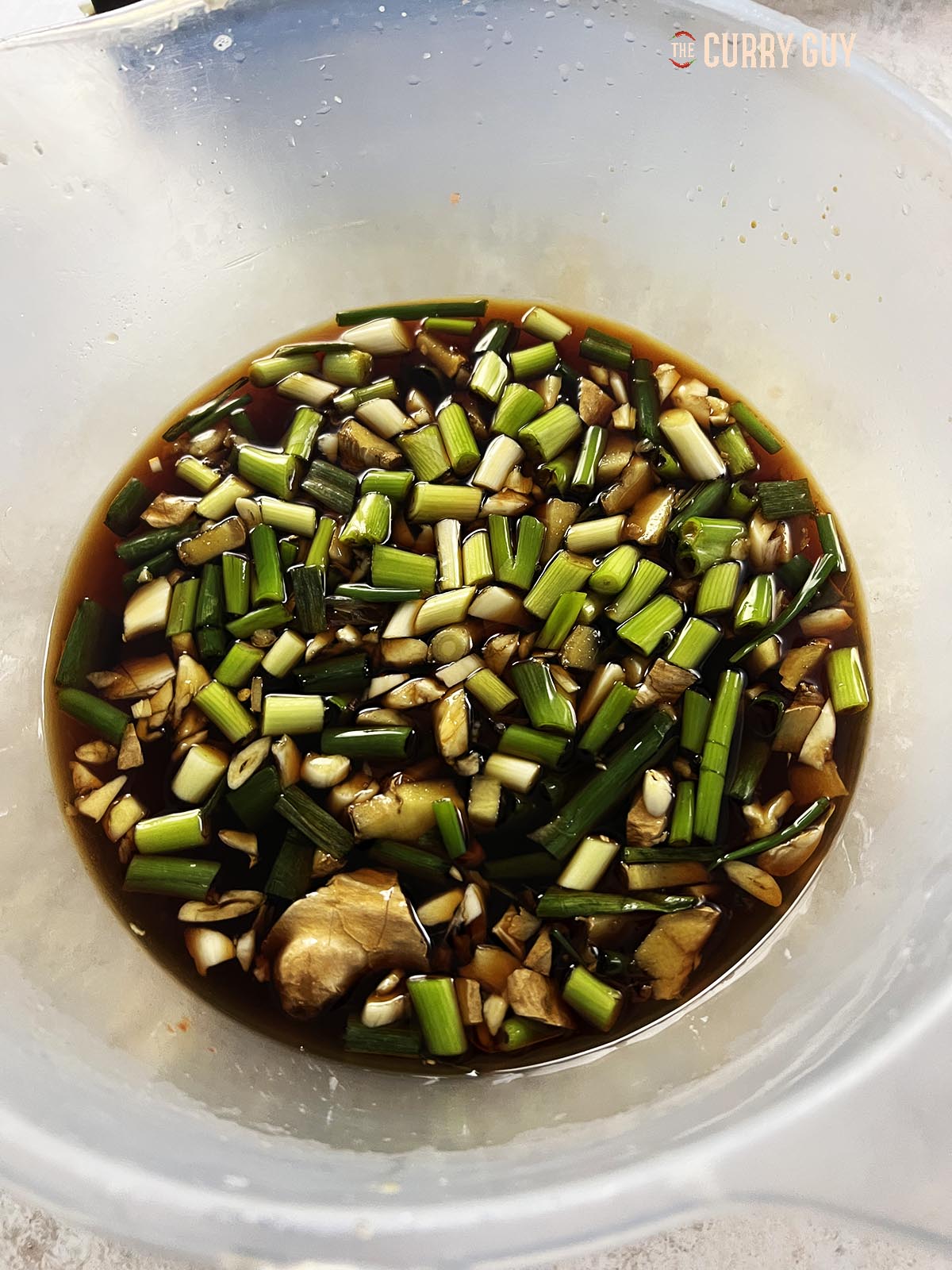 Adding the spring onions (scallions), garlic and ginger to the wet marinade ingredients. 