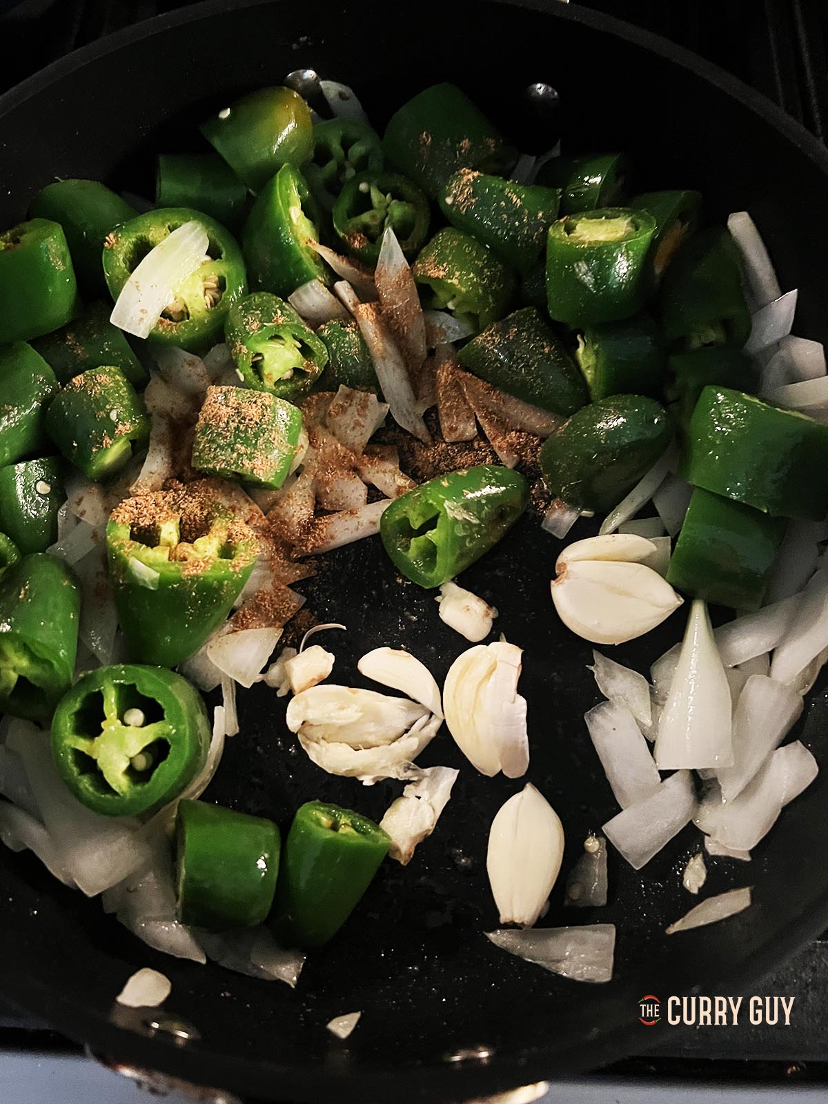 Frying the chilies, onion and garlic in the olive oil. Then adding ground cumin and salt.