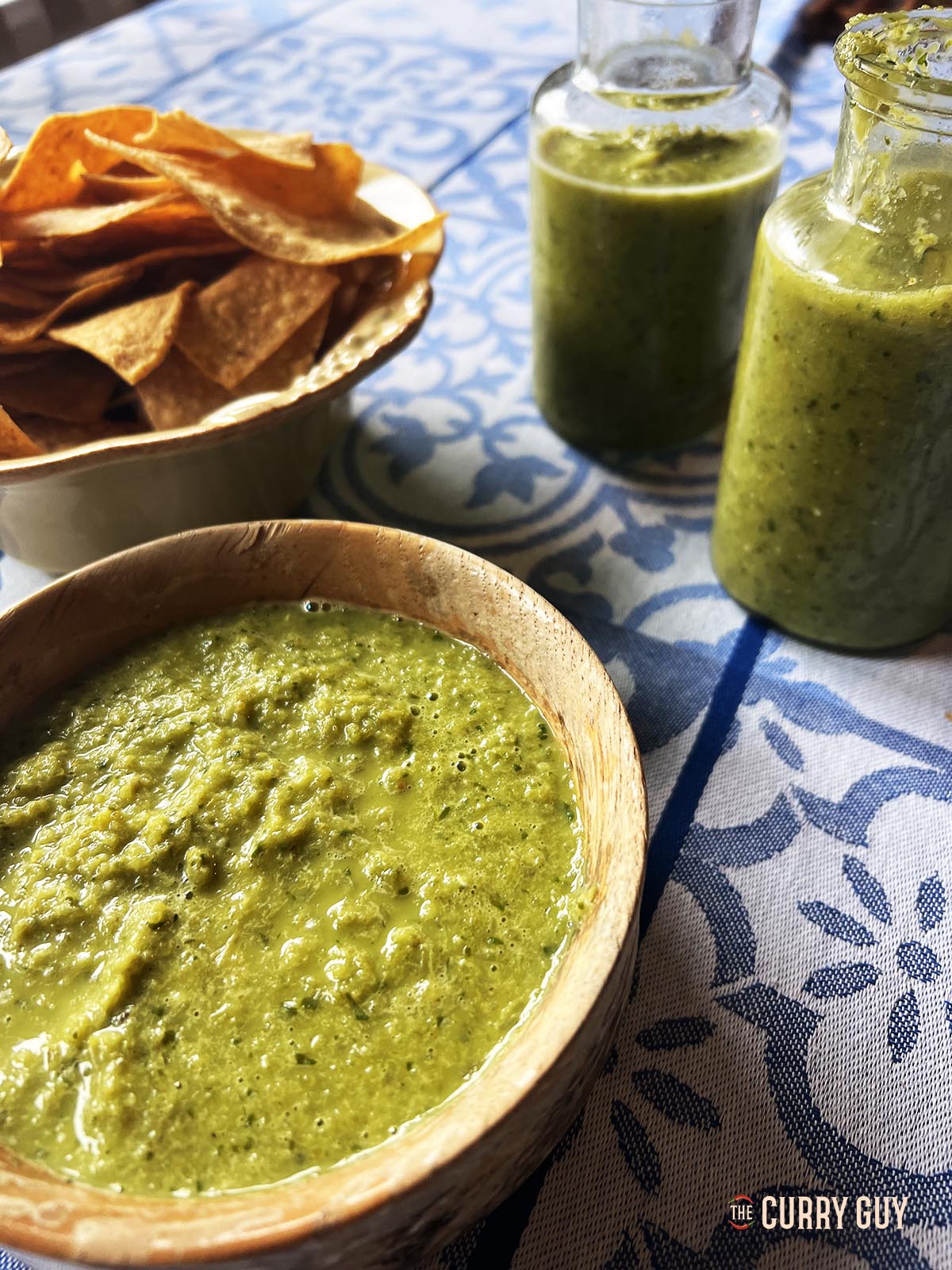 Jalapeño hot sauce served in a bowl with two jars of the sauce nearby.