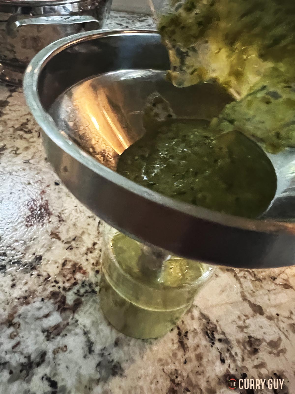 Pouring the finished hot sauce through a funnel into glass jars.