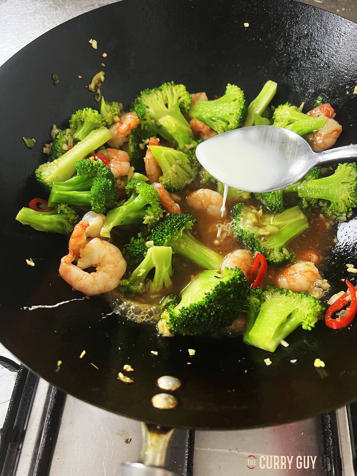 Adding the slurry to the sauce to thicken it some.