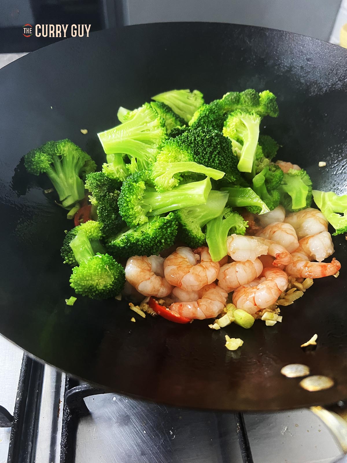 Adding the shrimp and broccoli to the hot wok.