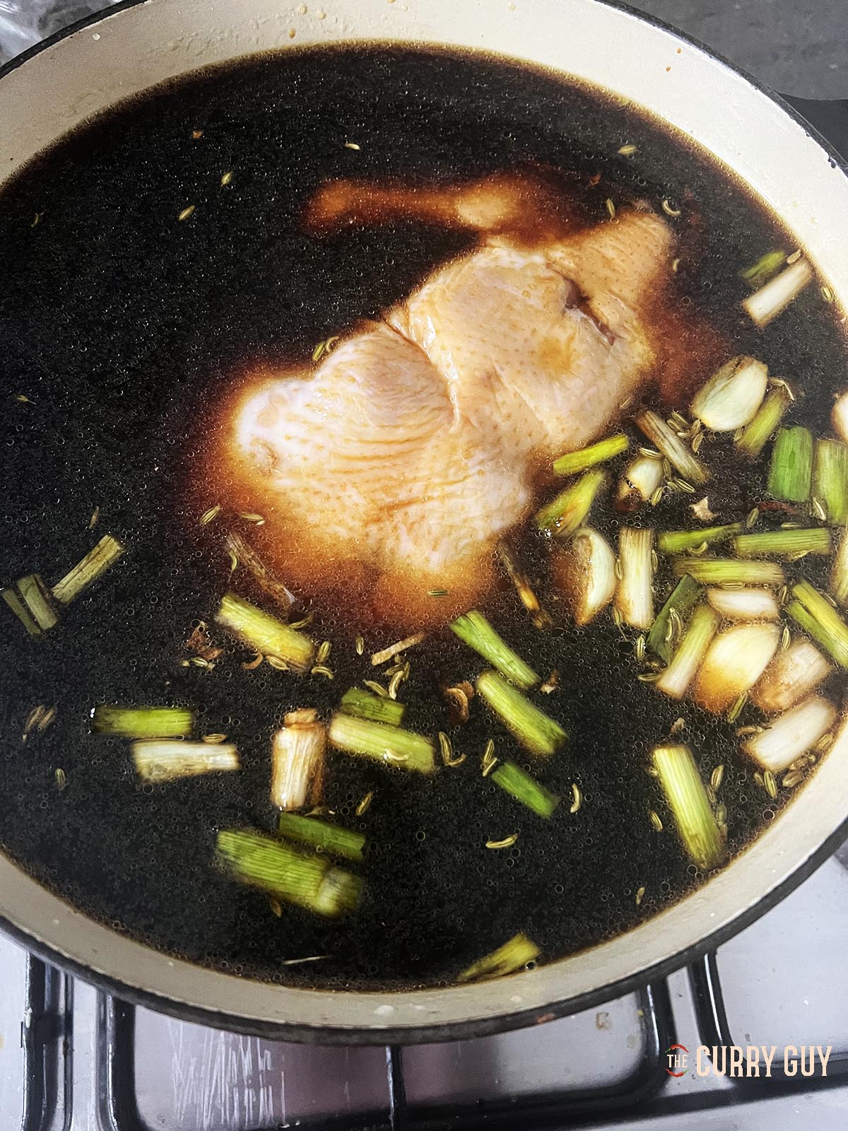 The chicken in the pot covered with the braising liquid.