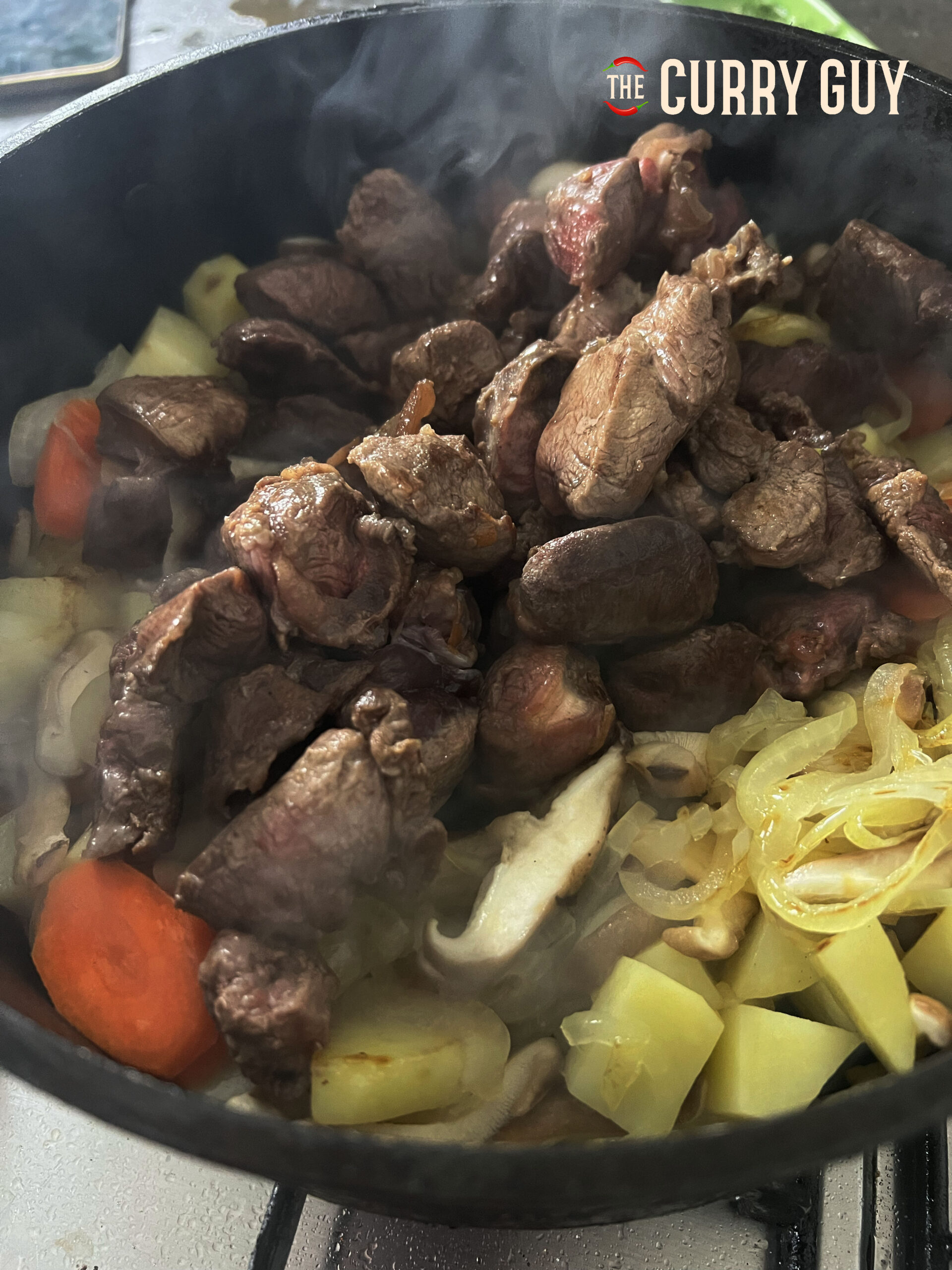 Adding the mushrooms and cooked beef to the pan.