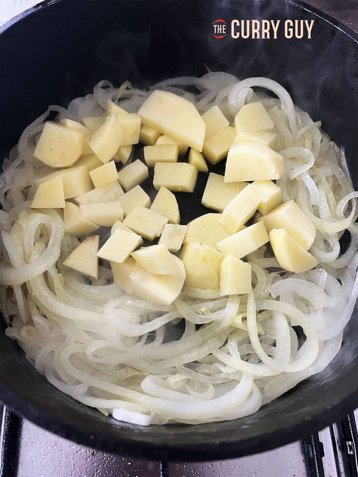 Adding the potato and carrot to the pan.