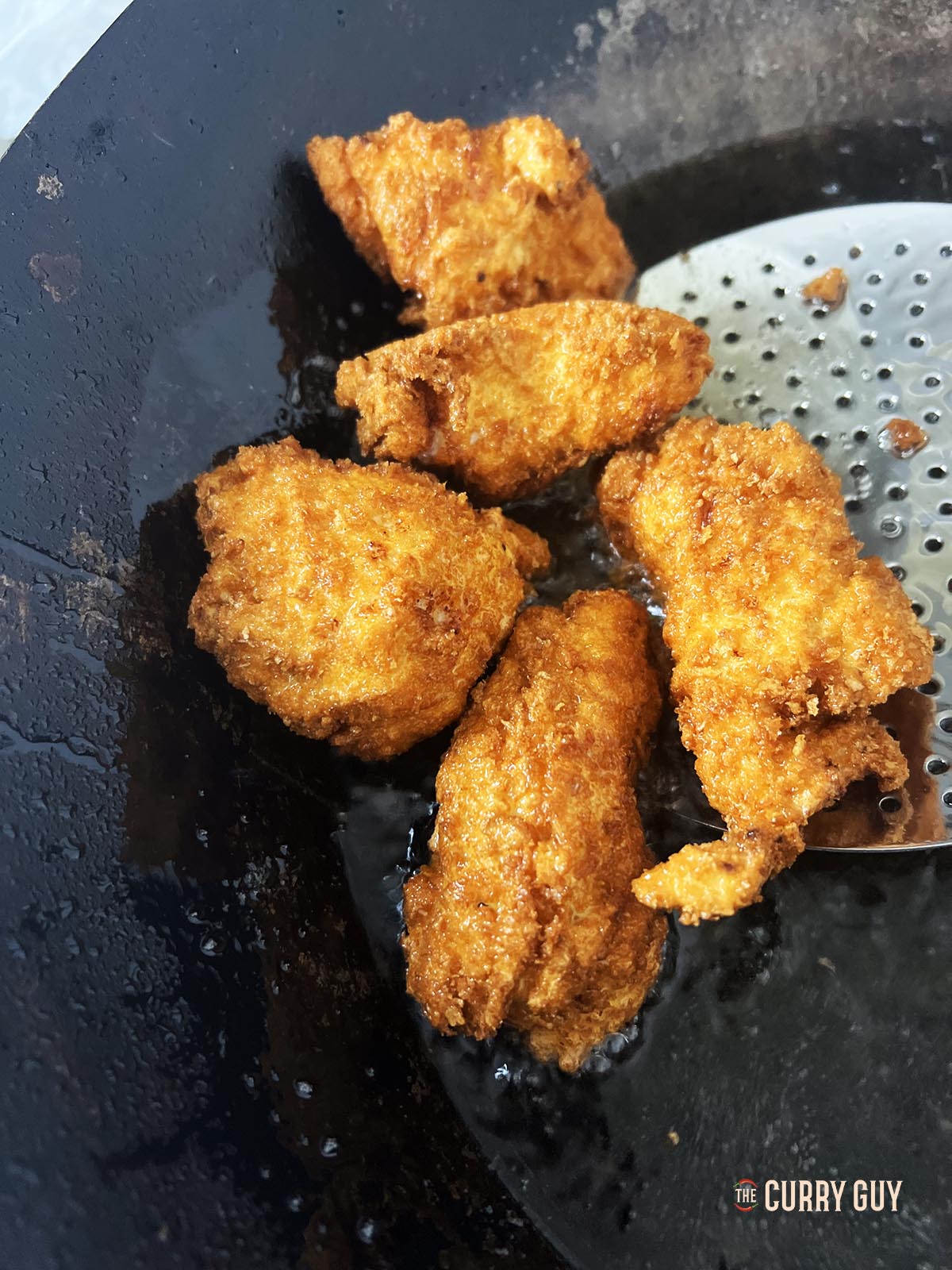 Transferring the cooked chicken to a paper towel to soak up any excess oil.