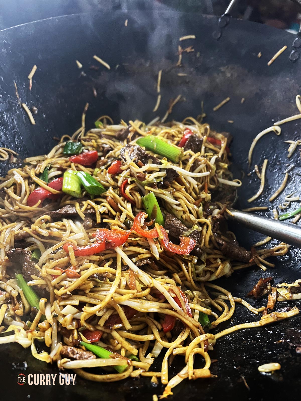 Stirring the beef chow mein together in the wok