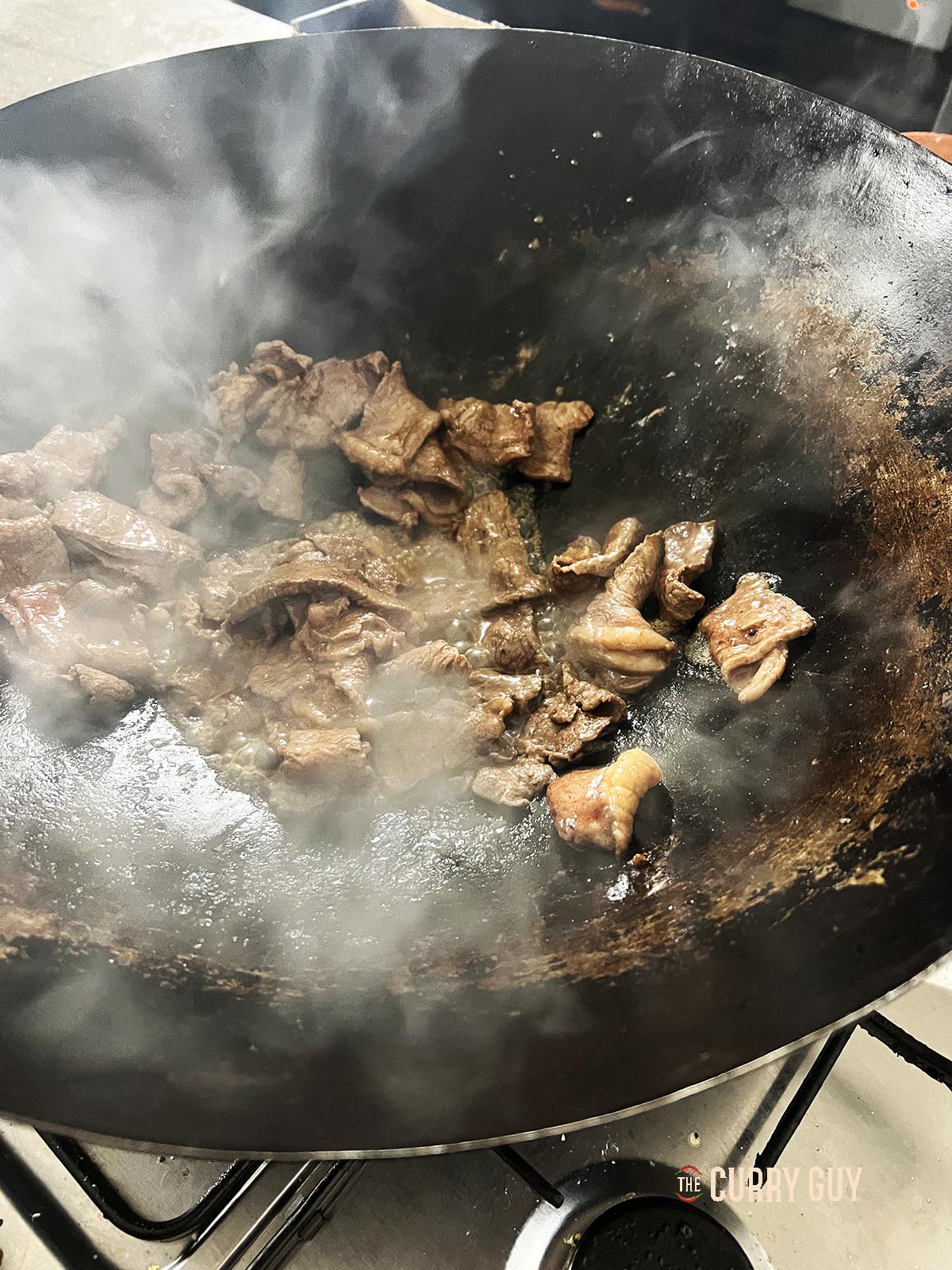 Frying the meat in a hot wok.