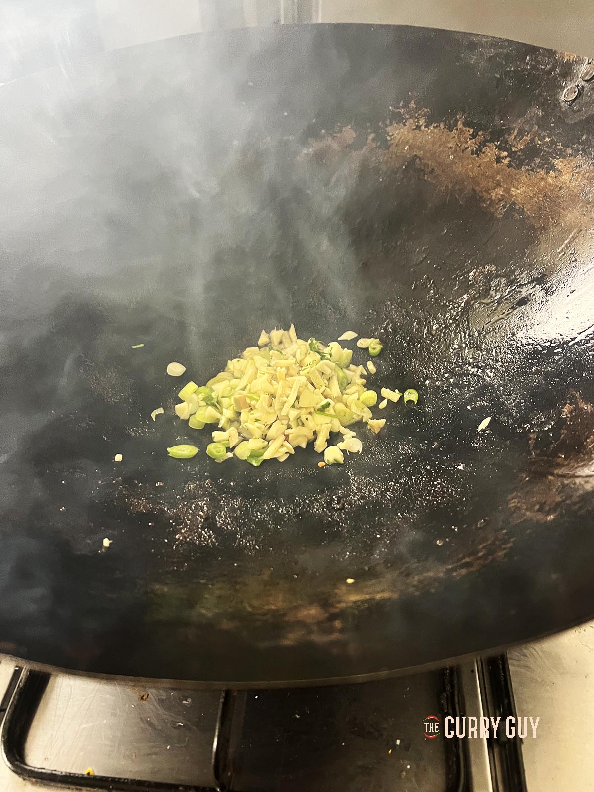 Frying the chopped garlic, ginger and spring onions (scallions).
