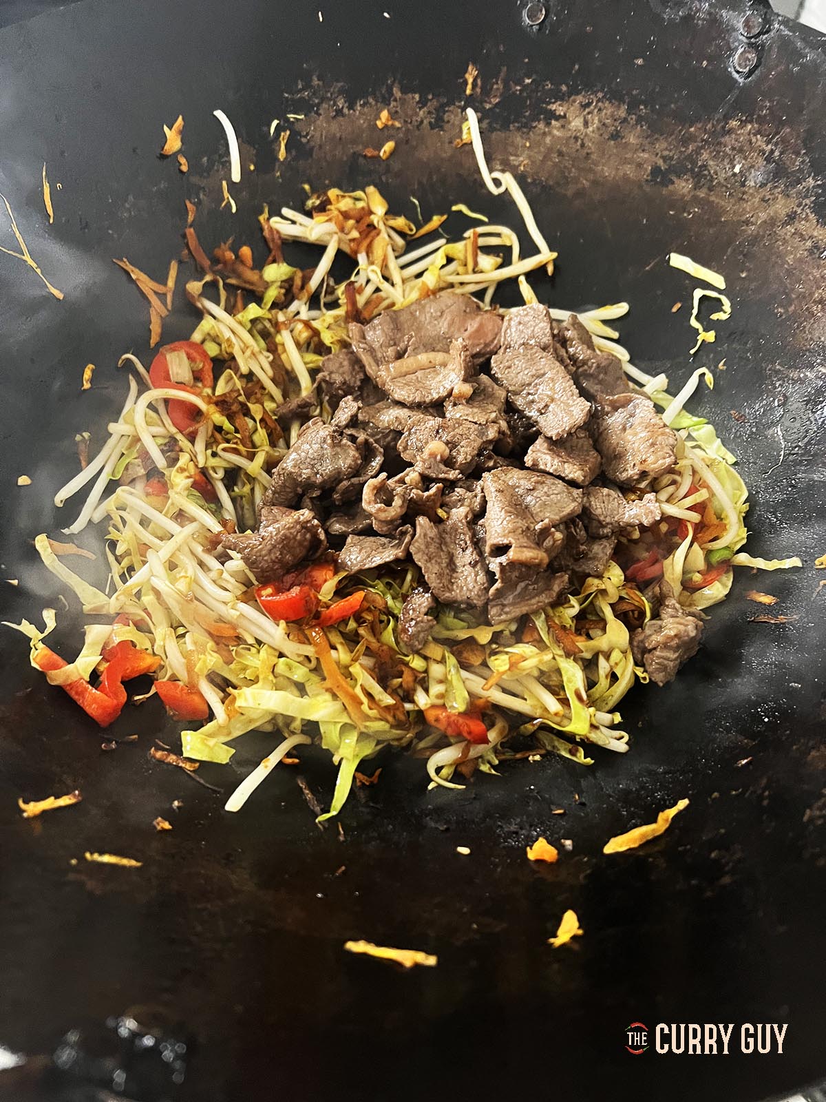 Adding the sauce, slurry and fried meat to the wok.
