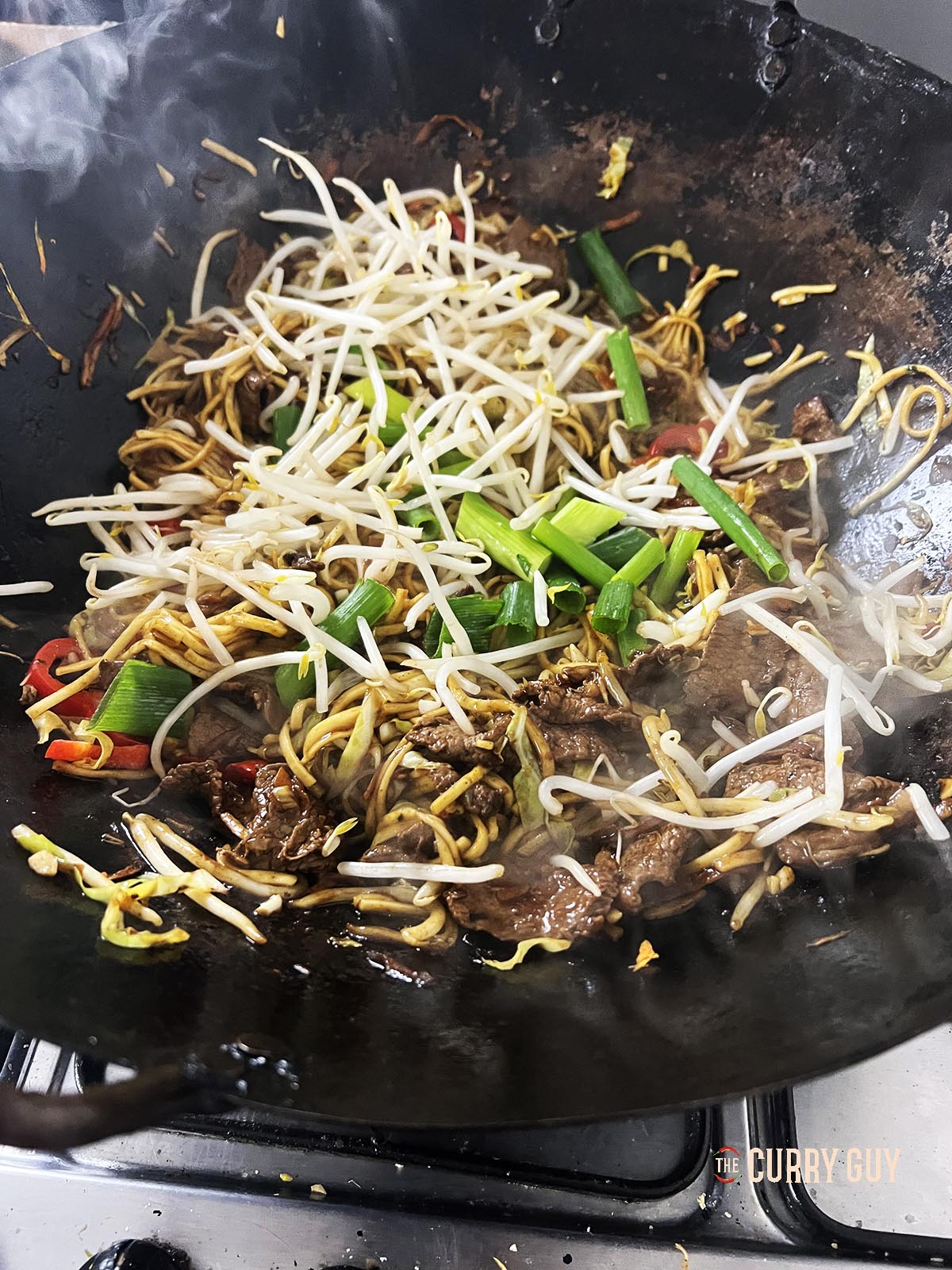 Adding the remaining bean spouts and spring onions (scallions) to the wok.