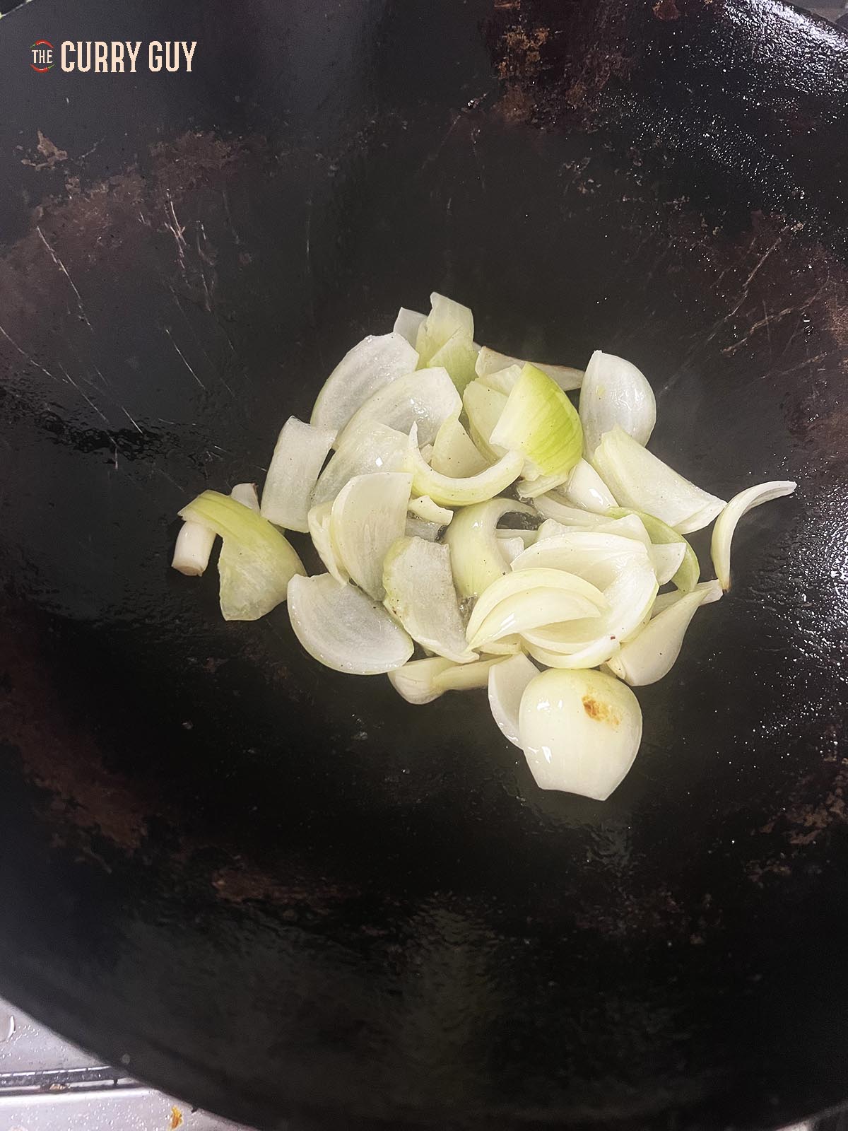 Frying the sliced onions in a wok.