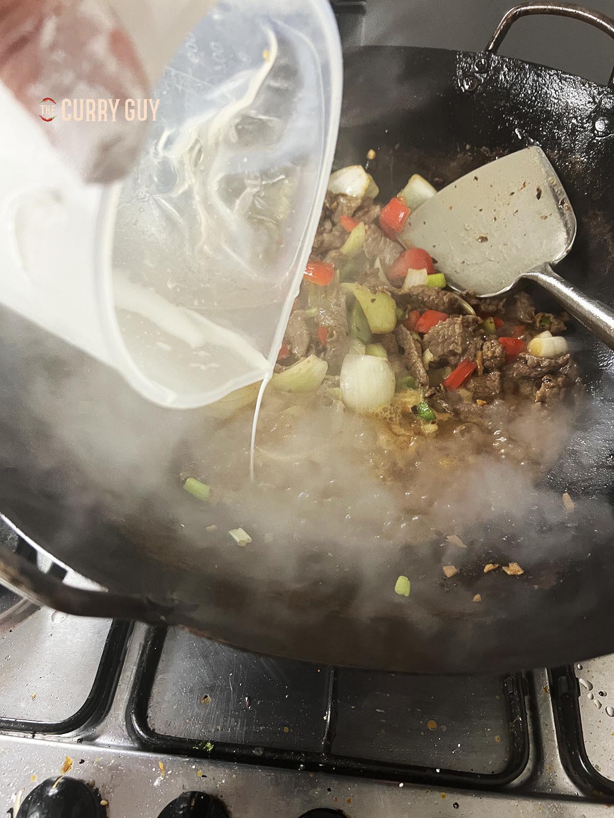 Adding the slurry to the sauce to thicken it.