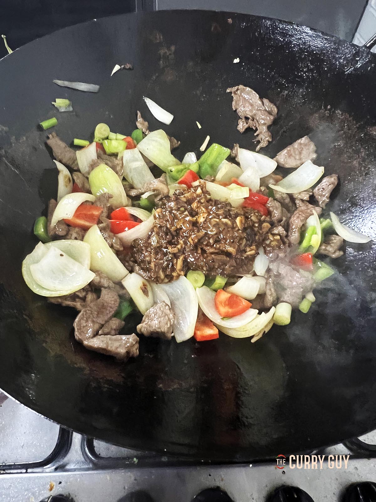 Adding the black bean sauce to the ingredients in the wok.
