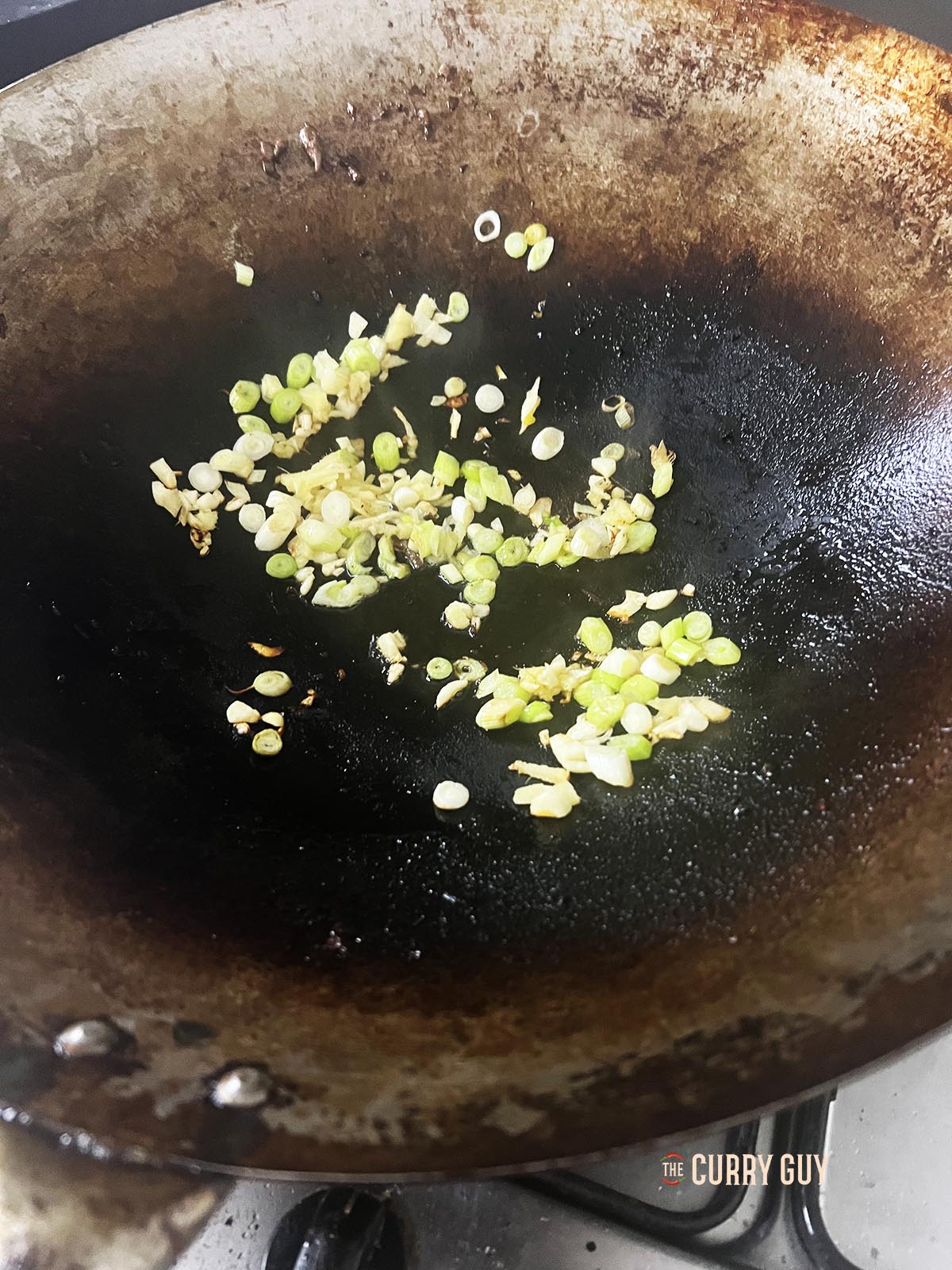 Frying the spring onions (scallions), ginger and garlic.