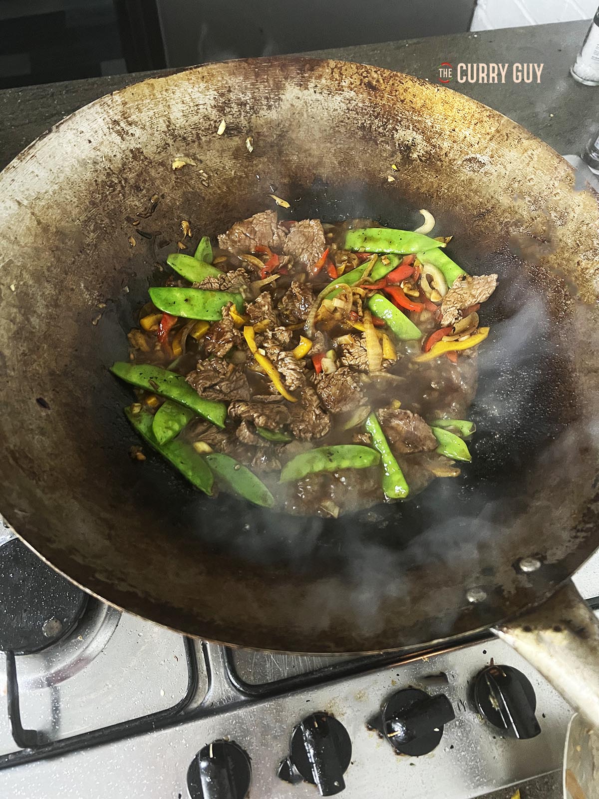 Stirring the beef into the sauce and vegetables.
