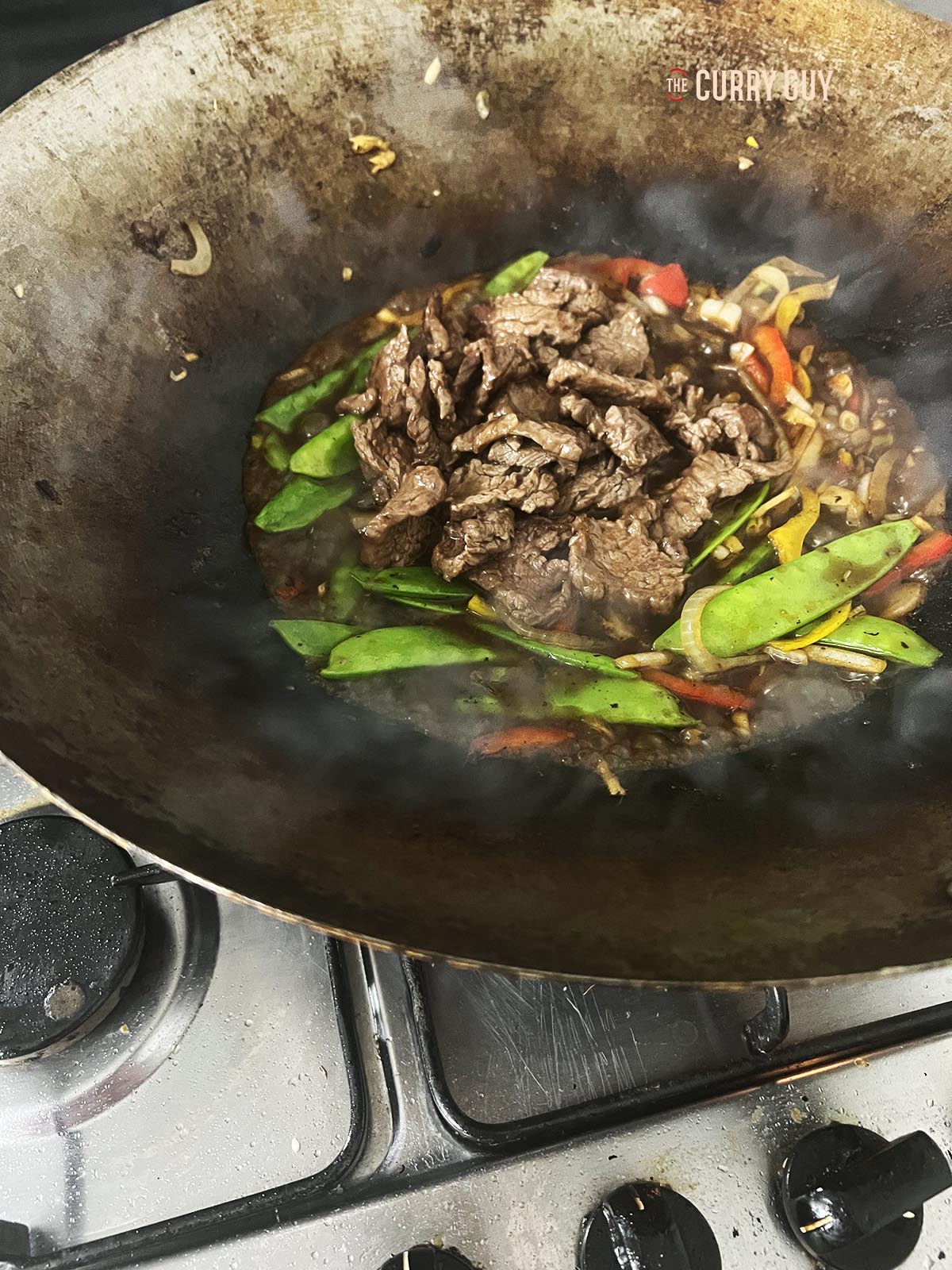 Returning the sliced beef to the wok.
