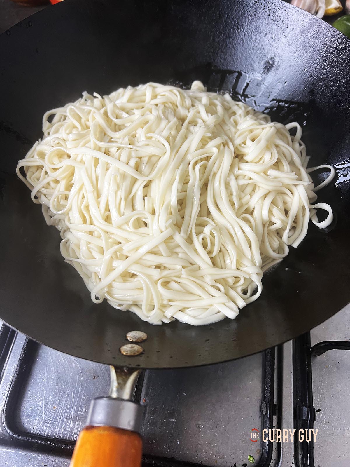 Adding the noodles to the oil in the wok.