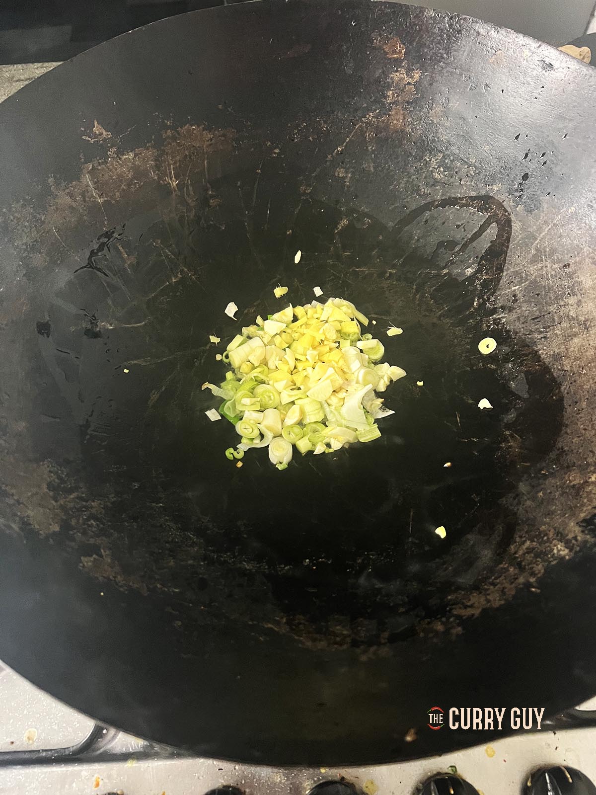 Frying garlic, ginger and spring onions (scallions) in a wok.