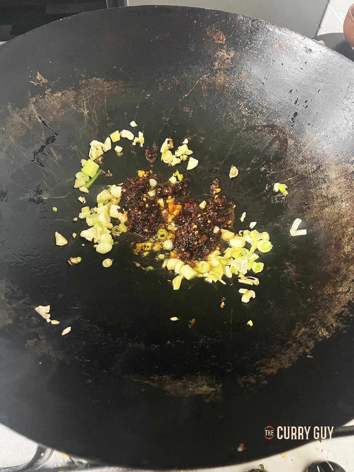 Adding the crispy chili oil to the wok.