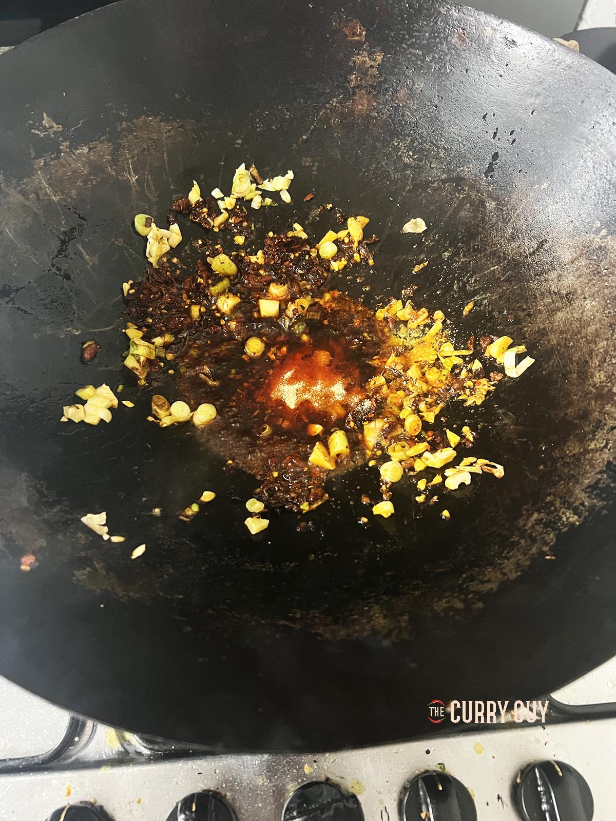 Adding the soy sauces, chicken bouillon powder, and sugar to the wok.