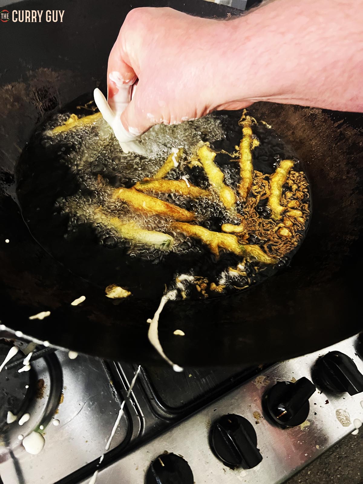 Adding the batter coated beans to the hot oil.